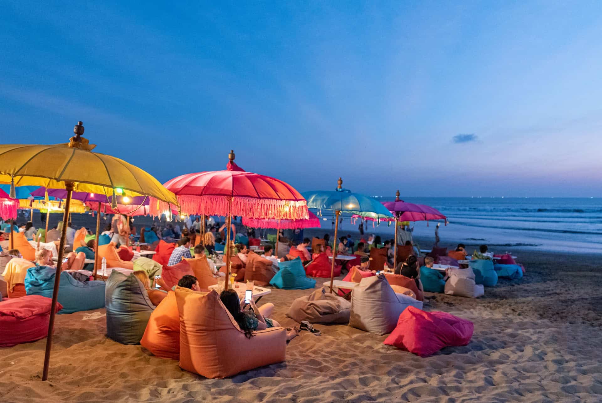 Poufs et parasols colorés sur une plage de Bali au coucher du soleil