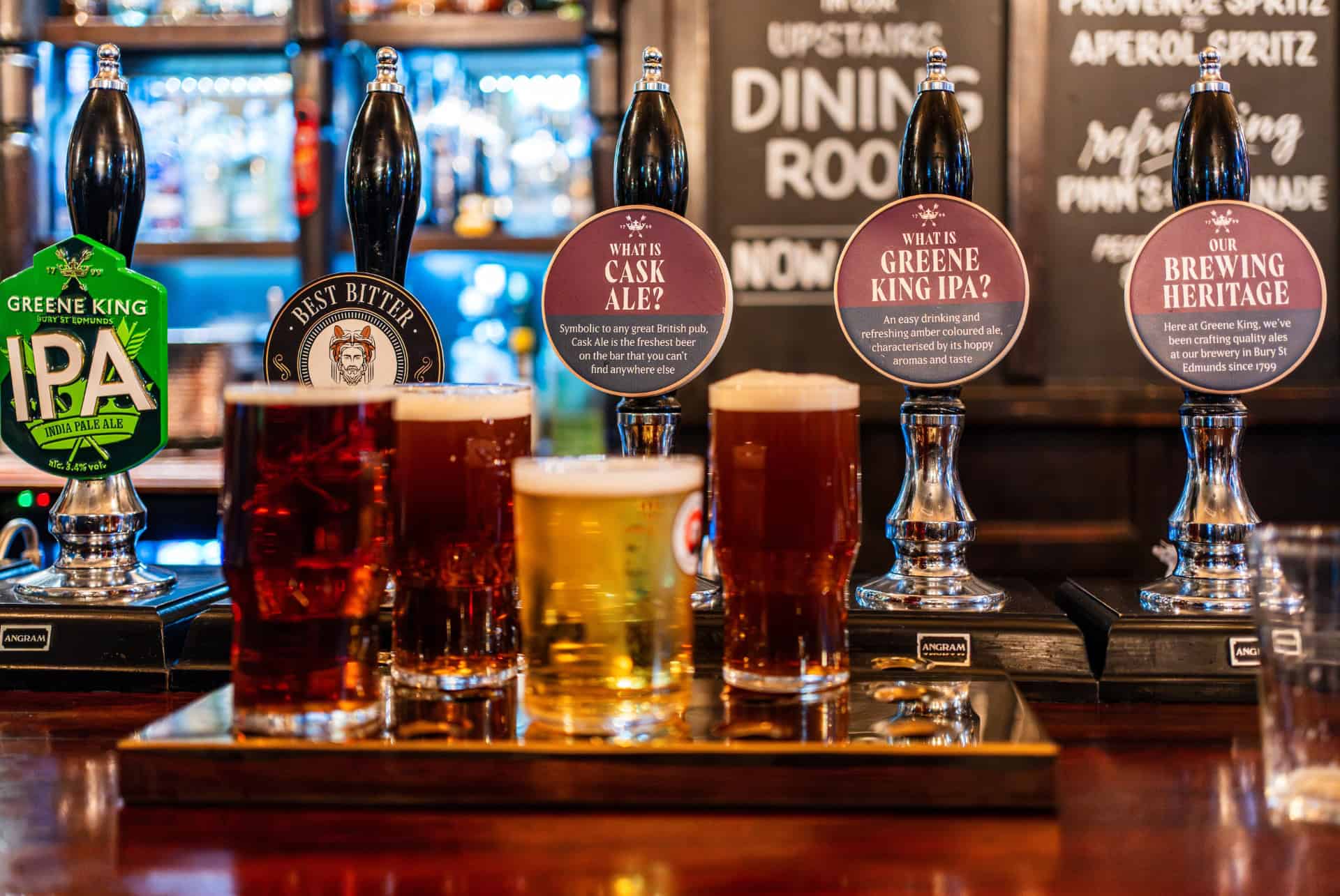 Pintes de bières britanniques alignées devant les pompes d’un pub londonien