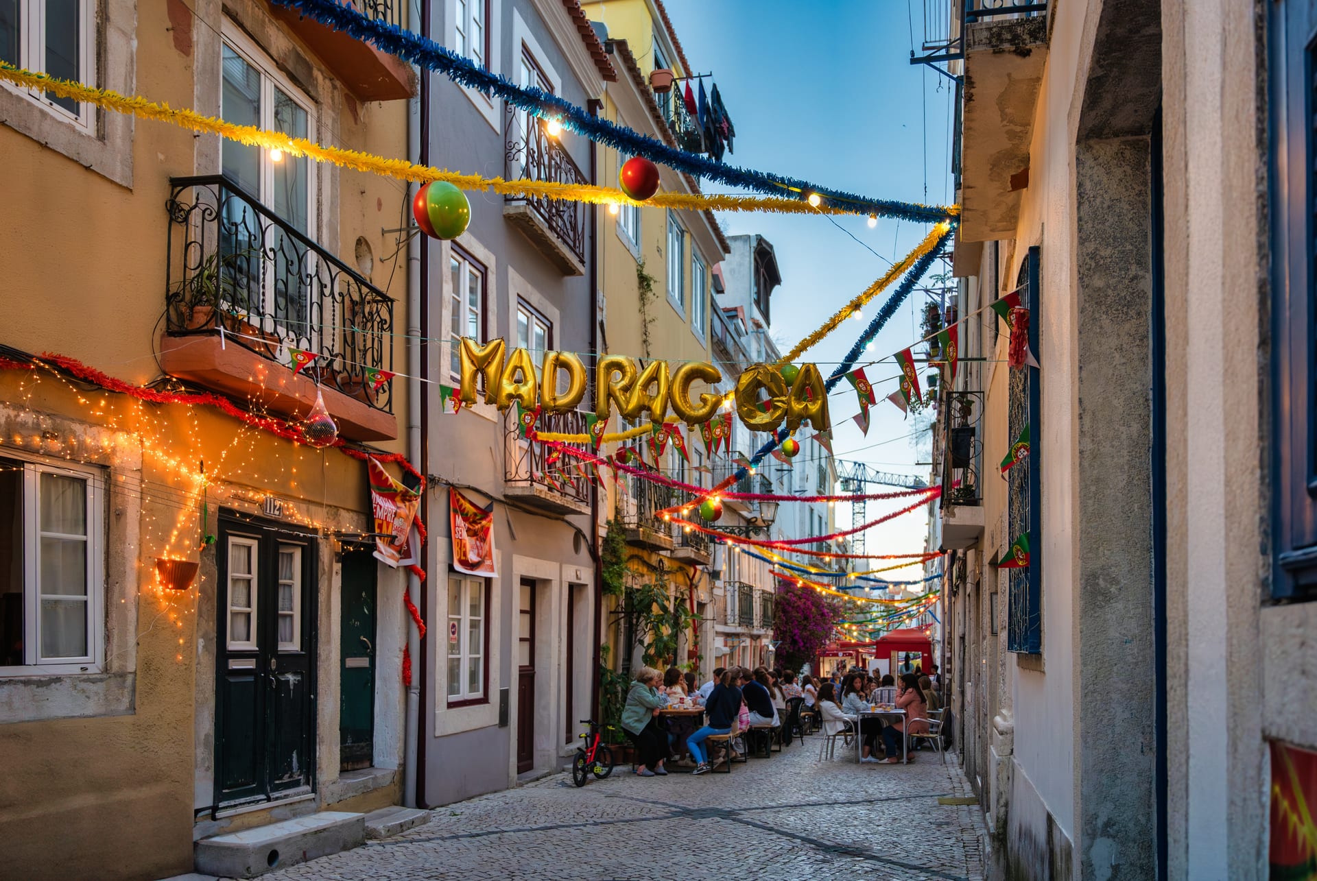Rue de Madragoa décorée de guirlandes et de ballons dorés pour les fêtes de juin