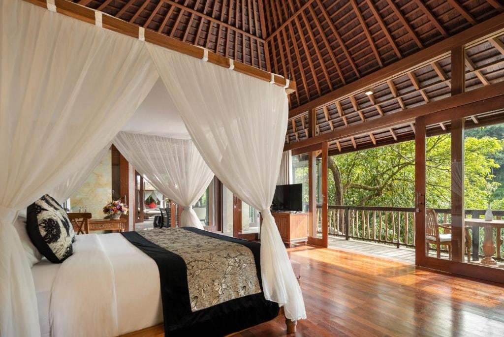 Chambre avec lit à baldaquin ouverte sur la végétation au Kayon Jungle Resort